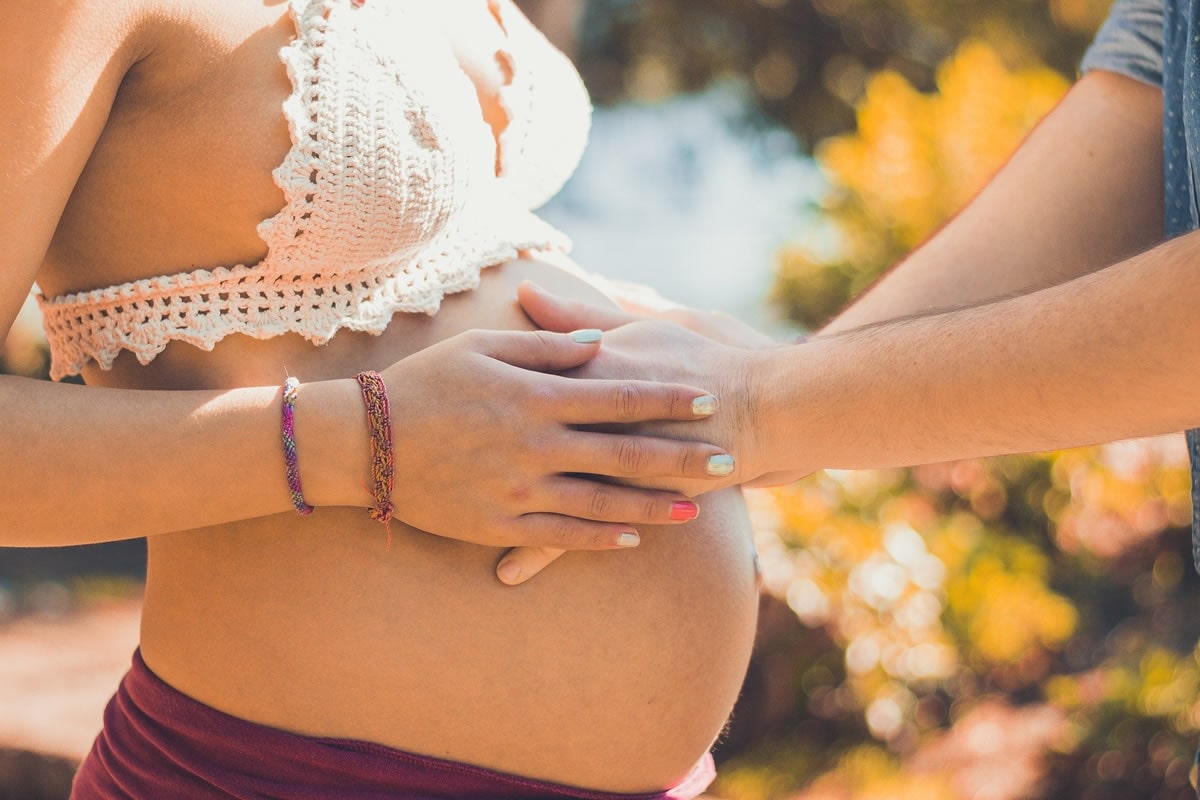 Zwei Hände liegen auf dem Bauch einer Schwangeren.
